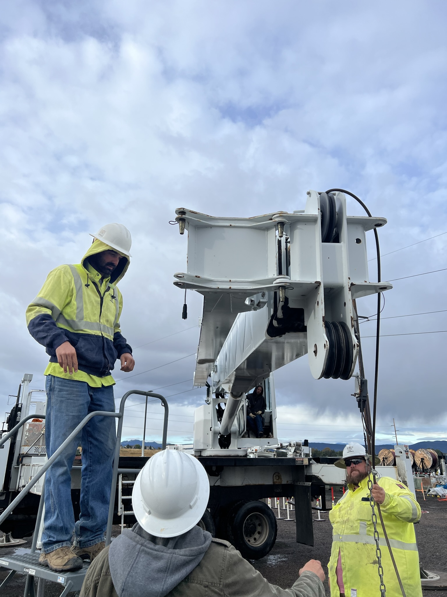 Image of three workers in high-vis vests reviewing the rigging on a crane | Crane Safe LLC