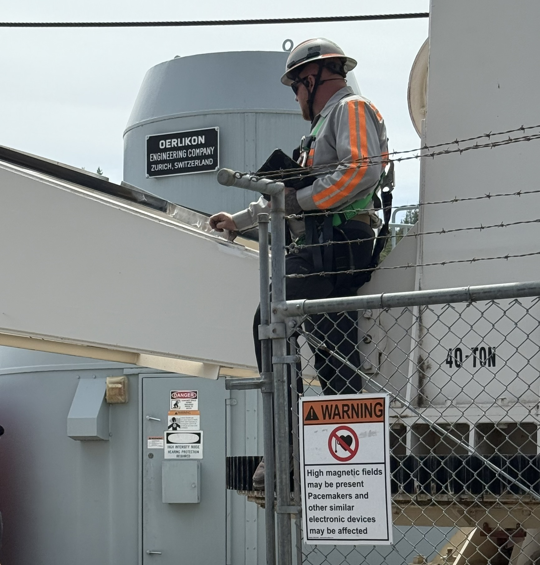 Image of Kevin Williams inspecting a crane next to a fence and a warning sign | Crane Safe LLC 